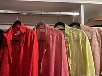 Five women's blouses hanging on a rod, showing colors red, pink, light green, beige, and a light pink blouse.