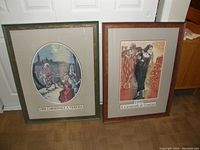 Photo of two framed prints leaning against a white door, showing the full pieces with visible titles referencing Venice Carnival 1999 in French and Italian, frames are wood with glass.