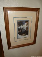 Framed print of a nature scene by Bev Doolittle hanging on a wall, showing the front view including the wooden frame and double matting.