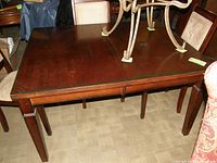 Rectangular wooden kitchen table with leaf extension and some visible wear on surface.