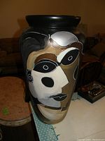 Full side view of the large vase showing the hand-painted abstract face in black, white, and brown colors on a black background. The vase is approximately 26 inches tall with a wide mouth.