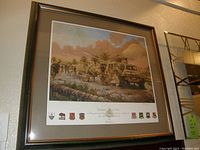 Photo showing the framed military scene print with soldiers, military vehicle and insignias below the image.