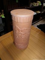Photo of vintage terra cotta wine chiller showing cylindrical shape with embossed grapevine design and textured band.