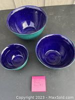 Photo of all three blue hand-crafted pottery mixing bowls, small, medium, and large sizes, arranged together showing interior deep blue glaze and turquoise exterior.
