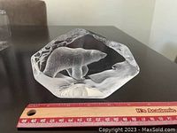 Front view of clear crystal sculpture with etched polar bear inside, shown next to a ruler for scale approximately 3 inches wide.