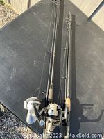 Two fishing rods approximately 6'6" long each, with attached reels laid on a black surface.