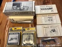 Boxed Woodland Scenics Scenic Details and Highway Miniatures horse-drawn wagons in original boxes displayed on wooden floor.