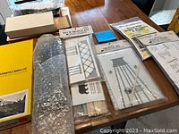 Overview of HO scale train lot showing packaged bridge kit parts, plastic components, and boxed model parts.