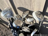 Close-up photo showing metal-headed Dunlop Loco woods and irons, some with protective covers, inside the golf bag.