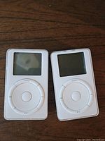 Front view of two iPod 1st gen shows screen and click wheel controls.