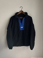 Front view of black and blue Palace shell popover jacket on hanger
