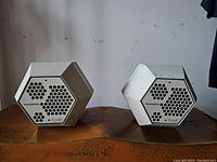 Pair of speakers side by side showing hexagonal shape and front grilles