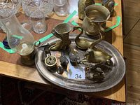 Image showing various brass and silver decorative items on a silver-colored tray including a boot-shaped container, small pitcher, and animal figurines.