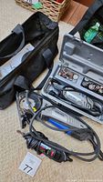Dremel rotary tools with cords, carrying bag visible in background
