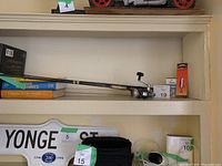 Fishing rod and reel placed on shelf with two lure packages beside it