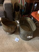 Overview of all three metal decorative pieces on carpet, including two oval buckets and one brass/bronze bucket with lion head detail.