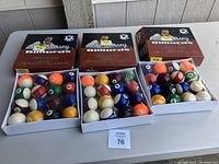Photo showing three open boxes of Mike Massey billiard balls with full sets of standard pool balls including striped, solid, and cue balls visible inside each box.