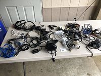 Overview of all cords and chargers spread on table with some cables coiled and others loose, showing variety of devices and connectors.