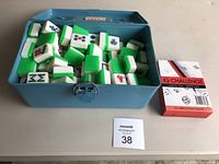 Blue plastic box open showing white Mahjong-style dominos with green backs inside.