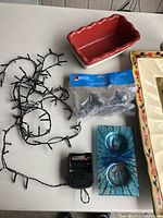 Red ceramic loaf pan, black string lights with battery pack, peacock feather decorative plaques, Avon Christmas tree cookie kit box