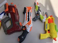 Close-up view of four foam dart blasters highlighting their different sizes and colors.