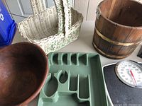 Photo showing white woven basket, wooden bucket, green plastic cutlery organizer tray, black kitchen scale