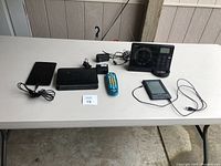 Overview of all electronics on table including router, tablets, remote, radio scanner, and cords
