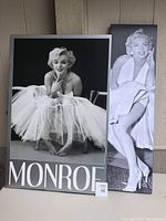 Two large black and white prints featuring Marilyn Monroe, one sitting barefoot in a tutu with 'MONROE' text, the other showing iconic dress pose.