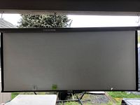 Full view of the movie projection screen mounted and showing the white screen area with black side and bottom borders.