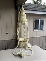 Full view of the hanging macrame plant holder with light attached, showing the woven cotton construction and tassels.
