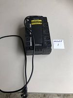 Front view of the black surge protector and battery backup device with power cord and outlets visible.