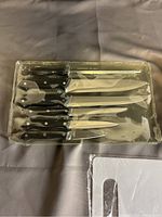 Image of set with five knives and a sharpener in sealed plastic packaging.