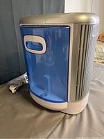 Air purifier unit showing blue translucent water tank with built-in handle and power cord