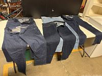 Five pairs of Gap jeans laid out on a table. Various denim washes including dark, medium, black and light blue. All appear new without tags.