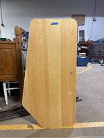 Photo of the wood desk top panel standing vertically showing its shape and surface