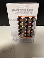 Box showing the Olde Thompson 20 Jar Spice Rack branding and features including real acacia wood and revolving carousel with 20 glass jars with embossed metal caps and sifter lids.