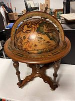 Full view of vintage Old World style globe on wooden stand with wheels in a room.
