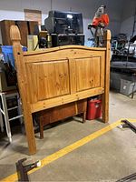 Front view of the full-size wooden headboard with metal rails and wheels, showing the natural finish and panel design.