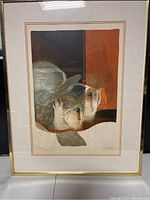 Framed lithograph showing abstract faces and embossed pattern