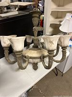 Front and side view of six-arm ornate chandelier with frosted glass shades and detailed metal work.