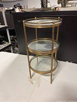 Full view of the brass and glass three tier side table showing overall construction and design.