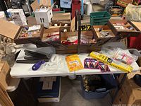 Front view of the fully expanded vintage wooden sewing box on a white table with many sewing threads and accessories inside.