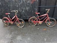 Two vintage Ross red kids bicycles side by side showing full profile with gas tank style frames, fenders, pedals, and reflectors.