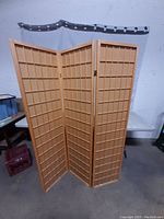 Full view of the 3-panel wooden room divider showing the lattice design and hinge connections.