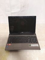 Front view of Acer Aspire laptop showing keyboard, screen, and stickers indicating Intel Core i3 and AMD Radeon graphics