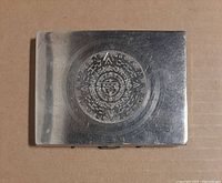 Top view of vintage silver cigarette case showing detailed Aztec calendar embossed design on lid.