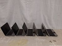 Side profile of five HP laptops showing their design and thickness, arranged open and facing left.