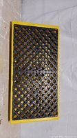 Top view showing the perforated black surface and yellow frame of the spill deck, clearly illustrating its grated design.