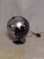 Light up globe shown from front angle with visible plug cord on surface
