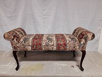 Front view of the mahogany Queen Anne style window bench showing upholstered seat with rolled arms and cabriole legs.